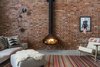 Modern home with Living Room, Hanging Fireplace, Concrete Floor, Sofa, Rug Floor, Ottomans, Lamps, Chair, Floor Lighting, Wall Lighting, and Wood Burning Fireplace. A bespoke flue was manufactured for the wood-burning fireplace to reach the 10-meter ceiling height. Photo 4 of Clerkenwell Cooperage