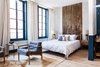 Modern home with Bedroom, Chair, Night Stands, Light Hardwood Floor, Rug Floor, Lamps, and Bed. The interiors are designed by Jersey Ice Cream Company. Accent walls, frames, and cabinetry are painted a deep cerulean blue for a calming vibe. Photo of Lokal Hotel