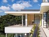 Plain steel windows and steel reinforced eaves differentiate the more recent wing from the original Queen Anne house. Natural white and charcoal black colours are a neutral backdrop for Bougainvillea and the blue of Sydney Harbour. Photo 13 of Twin Peaks modern home
