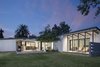Modern home with Grass, Back Yard, Exterior, House Building Type, and Wood Siding Material. The new addition on the right extends the original home roofline and adds a new covered patio area Photo of Schreiber House