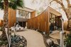 Modern home with Front Yard, Trees, Desert, Shrubs, Gardens, Walkways, Decomposed Granite Patio, Porch, Deck, Stone Patio, Porch, Deck, Exterior, and Wood Siding Material. Custom whimsical glass sculptures created by Rainier Glass Studio and succulents highlight the courtyard of this curved house in central Phoenix Photo of Curves House