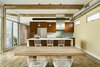 Modern home with Kitchen, Engineered Quartz Counter, Wood Cabinet, Porcelain Tile Floor, Glass Tile Backsplashe, Ceiling Lighting, Pendant Lighting, Refrigerator, Range Hood, Range, and Undermount Sink. The kitchen features a custom, stainless steel hood that is flush with the upper cabinets. Photo 11 of Sol House