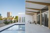 Modern home with Outdoor, Side Yard, Desert, Trees, Small Pools, Tubs, Shower, Hardscapes, Decomposed Granite Patio, Porch, Deck, and Pavers Patio, Porch, Deck. Cantilevered wood beams angle up towards the growing city skyline. On the left, a sloped area captures the monsoon rainfall and the Mulga Acacia trees will grow to the height of the home over time to provide more shade and privacy. Photo 8 of Sol House
