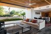 Modern home with Concrete Patio, Porch, Deck, Shrubs, Trees, Living Room, Front Yard, Sofa, Coffee Tables, Ceiling Lighting, and Concrete Floor. The walnut clad ceiling extends over the kitchen to the entry Photo 3 of Link House