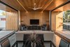 Modern home with Concrete Patio, Porch, Deck, Trees, Concrete Floor, Ceiling Lighting, Grass, Front Yard, Living Room, Chair, Sofa, and Coffee Tables. Walnut plywood with integrated LED lighting clad the open living space area, extending beyond the pocketing glass walls to the exterior Photo 9 of Link House