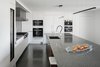 Modern home with Kitchen, Undermount Sink, Dishwasher, Wall Oven, Range Hood, Beverage Center, Refrigerator, Cooktops, White Cabinet, Wine Cooler, Concrete Floor, Engineered Quartz Counter, Wood Cabinet, Microwave, Ceiling Lighting, and Stone Slab Backsplashe. A neutral palette was selected by the homeowner throughout to make the red rocks and the views the star Photo 19 of Red Rocks