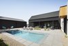 Modern home with Exterior, Gable RoofLine, Metal Roof Material, Metal Siding Material, Wood Siding Material, and House Building Type. The L-shaped house plan with a detached garage create a 3 sided courtyard, providing privacy and shade in the urban, desert lot. A small pool is the focus of the backyard living Photo 7 of Pleats