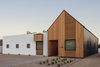 Modern home with Exterior, Stucco Siding Material, Gable RoofLine, Wood Siding Material, House Building Type, Flat RoofLine, and Metal Roof Material. The house draws its name, “Pleats,” from the corrugated metal that wraps the gabled volume, reminiscent of the pleated exterior of the Saguaro cactus. Photo of Pleats
