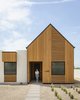 Modern home with Exterior, Stucco Siding Material, Flat RoofLine, Wood Siding Material, Gable RoofLine, House Building Type, and Metal Roof Material. The gabled entry features a patterned, wood rainscreen that evokes the forked ribs of the Saguaro cactus while the recessed entry is akin to a Saguaro boot, the holes in the giant cacti that many desert animals use as their homes. Photo 2 of Pleats