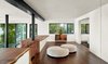 Modern home with Living Room, Ottomans, Bookcase, Ceiling Lighting, Recessed Lighting, and Dark Hardwood Floor. The yoga and meditation area is placed on the upper level, which also features a partitioned bedroom and private bath. The warm wood floors are heated by hydronic tubes below, while supplemental and more instant heat is provided by a concealed infrared heater in the ceiling. Greenery surrounds the sides of the property for a serene environment. The industrial supports required to hold the 3 floors above were left exposed, and the burled redwood slabs are exposed and serve as the ceiling and sides to the spaces below. Photo 4 of Twin Peaks Escape Pad