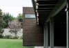 Modern home with Grass, Concrete Patio, Porch, Deck, Exterior, Wood Siding Material, and House Building Type. At the rear addition, the existing overhang meets the new cedar mass to divide the length of the covered patio and create outdoor spaces of varying size. Photo 16 of Villa Park Modern