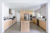 Modern home with Kitchen, Engineered Quartz Counter, Metal Counter, Wood Cabinet, White Cabinet, Concrete Floor, Metal Backsplashe, Ceiling Lighting, Pendant Lighting, Range, Wall Oven, Dishwasher, Microwave, Cooktops, Refrigerator, Range Hood, and Undermount Sink. The new open kitchen features maple, quartz, steel + concrete finishes, as well as a custom slatted maple and plywood island. Photo 6 of Villa Park Modern