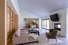 Modern home with Living Room, Chair, Sofa, Table, Ceiling Lighting, Concrete Floor, and Two-Sided Fireplace. The open floor plan features a bi-folding door system and dual-sided fireplace to provide a strong connection to the rear landscape and views. Photo of Villa Park Modern