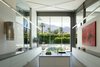 Modern home with Kitchen, Concrete Floor, Concrete Counter, Pendant Lighting, White Cabinet, Range Hood, Range, Refrigerator, Wine Cooler, and Undermount Sink. The glass wall on one end of the kitchen frames the mountain views. The cabinetry, all glass-fronted lowers, with a convection stove and cylindrical vent make this room about the view and the art. Photo 3 of Desert Canopy House
