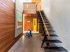 Modern home with Concrete Counter, Wood Cabinet, Metal Cabinet, Concrete Backsplashe, Refrigerator, Wall Oven, Cooktops, Range Hood, Dishwasher, Undermount Sink, Bed, Chair, Track Lighting, Storage, Ceiling Lighting, Medium Hardwood Floor, Back Yard, Walkways, Trees, and Shrubs. Entry and stairs Photo 8 of Land Park Residence