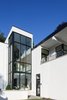 Outside, strong roof overhangs accentuate the horizontality of the modern white stucco facades and natural limestone provides a counterpoint to the smooth white stucco. The limestone not only grounds the house but serves as a symbolic link to the couple’s previous residence, which also featured similar stonework. Photo 6 of Woodland Road Residence modern home