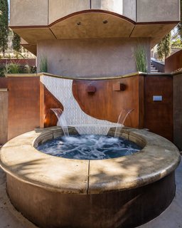Spa under detached hillside cantilevered studio. Coping is poured in place concrete while surround is prematurely rusted steel.