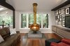 The original Malm fireplace sits atop its new tiled platform in the opened up living room. Since the home's setting feels very park-like, the new covered deck - visible just outside the windows - was designed to add year-round living space to the home. Photo of The Ping Pong Home modern home