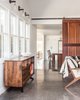 Modern home with Living Room, Concrete Floor, Wall Lighting, Chair, Console Tables, and Bookcase. concrete floors in family room Photo of Wild Way Remodel