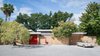 The Pavilion House's outer wall encircles a snaking courtyard that connects many of the home's interior spaces. After a step inside the lipstick red door, guests are greeted with an entrance into the home's exterior or to private patio on the left. Within that outer wall, both indoor and outdoor spaces appear to be one in the same. Photo of The Pavilion House modern home