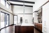 Modern home with Kitchen, Wood Cabinet, Stone Counter, Pendant Lighting, White Cabinet, Wood Backsplashe, Dark Hardwood Floor, Beverage Center, Range Hood, Cooktops, Wall Oven, Refrigerator, and Recessed Lighting. The open concept design in this cabin features wooden details and a white kitchen.
Photo of Modern Cabin in Ste-Adele