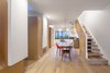 Modern home with Dining Room, Medium Hardwood Floor, Light Hardwood Floor, Pendant Lighting, Accent Lighting, Table, Bar, Slate Floor, and Chair. Dining area and kitchen beyond. Service pods on the left create distinction between areas along the open plan Photo 5 of House Grace