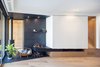 Modern home with Living Room, Wood Burning Fireplace, Corner Fireplace, Slate Floor, Light Hardwood Floor, Accent Lighting, Bookcase, and Medium Hardwood Floor. Black slate hearth with wood stove. Millwork pod conceals entertainment area when not in use Photo 7 of House Grace