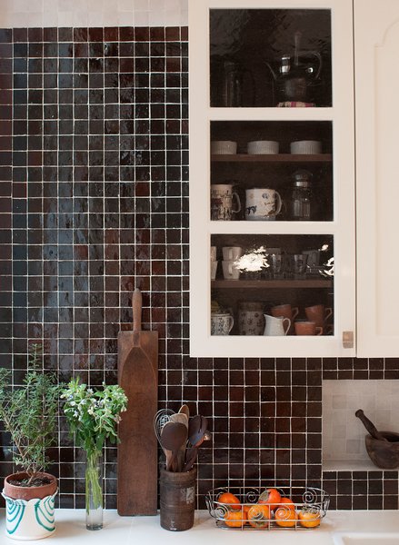 The mixture of dark colored hand-made Moroccan tile backsplash by Mosaic House is offset by  contrasting niche lined with light-colored tile. The custom kitchen cabinets were designed by MIRIAM BIOLEK Interior Design with Bendheim's mouth-blown glass inserts.