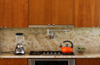 The kitchen was designed to be as sleek and minimalist as possible, yet remain "warm" to the eye. Unlike a range, a cooktop and oven do not disrupt the line of the countertop. The range hood is mostly hidden and only shows a thin horizontal line tucked within the line of the cabinets. It pulls out when in use, and slips back into line with the cabinets when not. Photo 8 of The Goat Sheds modern home