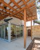 The Master Bedroom shed is surrounded by a covered cedar porch. Two 12' walls of sliding glass converge at a corner to visually and physically connect the room to the outdoors. The roof overhangs and porches offer exposed wood rafters and beams. The cedar rafters, beams, and posts as well as the stone walls complement and "warm up" the corrugated metal siding. Photo 12 of The Goat Sheds modern home