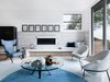 Modern home with Living Room, Chair, Ribbon Fireplace, and Coffee Tables. "The first piece we designed for the great room was the custom sofa. It has a unique shape with a 45-degree angle that allows views in multiple directions. We then continued with different accent pieces like the vintage chairs from Alex Fradin and the gorgeous Vladimir Kagan wing back chair. I chose both because they reminded me of the type of angular seating you'd see in a high end sports car. Our client loves to race cars and the wing back is his favorite piece in the room. For the artwork above the fireplace, I was looking for something clean that would bring your eyes up. When I found these striking black and white works by Justyn Chapman, I knew they'd be perfect." Photo of Contemporary Cool Sausalito Bachelor Pad