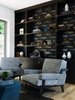 Modern home with Office, Shelves, Storage, Library Room Type, Bookcase, and Chair. "Then came the library--what a fun room to design! We wanted this space to have a bit of the unexpected while still maintaining the feel of a formal library--a place you might end the day with an after dinner drink. When we found the amazing "Bruce" wallpaper by Abnormals Anonymous, we could not resist. I think we can all agree that a stripped down whale is a bit unexpected! Its such a fun design element and I loved the idea of bringing an ocean reference into the room. The space also includes a TV which we hid behind a door panel. I added brass side brackets to the built-ins draw your interest to the shelving and further the focus on the fabulous Bruce wallpaper. I always like to add a little jewelry to my cabinetry, and this was an fun way to do it." Photo 10 of Contemporary Cool Sausalito Bachelor Pad