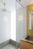 Modern home with Wall Lighting. The lower bathroom was transformed as well and Murdock added another glass panel to this space to bring in light from the window in the adjacent room. The mustard yellow tile from Heath Ceramics adds a fun pop of color and Murdock's tile layouts were meticulously planned to seamlessly intersect with adjacent materials and cabinetry. Photo 15 of Details Make the Difference in this San Francisco Urban Loft