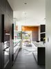 Modern home with Kitchen, Engineered Quartz Counter, Porcelain Tile Floor, Colorful Cabinet, Wood Cabinet, Ceiling Lighting, Recessed Lighting, Refrigerator, Accent Lighting, Wall Oven, and Undermount Sink. View from Pantry to East Patio through the Kitchen Photo 6 of the Duncan Residence