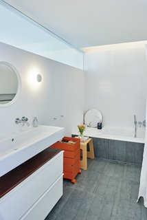 A horizontal glass pane stretches the length of the bathroom, illuminating the redesigned space from above.