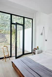 A look into one of the home's serene bedrooms, featuring a soothing neutral color palette and direct access to the outdoors.