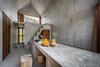 Modern home with Kitchen, Concrete Counter, Pendant Lighting, Concrete Floor, and Drop In Sink. The concrete countertops, walls, and staircase echo the home's refined modern design aesthetic. Photo 5 of La Casa Pequena