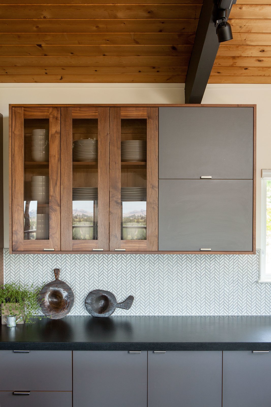 A backsplash laid out in a herringbone pattern adds a subtle layer of texture while pendant lighting adds depth.