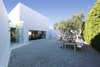 Three mature Olive trees and a floor of gravel which gradiates from dark to light gray are viewed from the living room gallery. Photo of A New Stage modern home