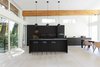 Modern home with Kitchen, Pendant Lighting, Ceiling Lighting, and Light Hardwood Floor. MIZA Architects completely renovated the Capilano Crescent Residence. Nestled in the trees, the home is filled with light and plenty of space. The black kitchen offers a contemporary contrast to the white walls and light hardwood floors. Photo 3 of Capilano House