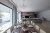 Modern home with Chair, Light Hardwood Floor, Lamps, Ceiling Lighting, Pendant Lighting, and Travertine Floor. Living room and dining area looking over the private garden Photo 17 of A House in Yarmouk
