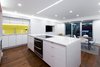 Modern home with Kitchen, Medium Hardwood Floor, Dishwasher, Microwave, Wood Backsplashe, Undermount Sink, White Cabinet, Wall Oven, Cooktops, Engineered Quartz Counter, Accent Lighting, Ceiling Lighting, and Ceramic Tile Backsplashe. View of Kitchen area Photo 10 of DC Waterfront Residence