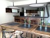 Modern home with Kitchen, Refrigerator, Range, Range Hood, Wood Cabinet, Light Hardwood Floor, Pendant Lighting, Metal Backsplashe, Recessed Lighting, and Drop In Sink. Detail of dining area to kitchen Photo 9 of The River House