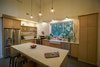 Modern home with Kitchen, Engineered Quartz Counter, Dishwasher, Concrete Floor, Refrigerator, Wood Cabinet, Subway Tile Backsplashe, Pendant Lighting, Wall Lighting, Range, Open Cabinet, and Drop In Sink. The open kitchen is a study in simplicity. White subway tile defines the vertical space beneath the high, vaulted ceiling and edges of a large window over the sink. In a modern farmhouse, minimal wood cabinetry, countertops, and open shelving are the antithesis of country kitsch. Photo 10 of Modern, Passive, Net Zero Farmhouse