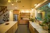 Modern home with Kitchen, Subway Tile Backsplashe, Concrete Floor, Engineered Quartz Counter, Pendant Lighting, Drop In Sink, Dishwasher, Refrigerator, Range, Wall Lighting, and Wood Cabinet. The custom cupboard at the end of the kitchen is thoroughly modern yet it recalls the rustic cupboards of pre-1920s farmhouses before built-in cabinets existed. A thoughtful detail: The lower cabinets and island also have “feet” like old freestanding cupboards. Photo 12 of Modern, Passive, Net Zero Farmhouse