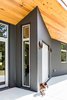 Modern home with Exterior, Metal Roof Material, House Building Type, Concrete Siding Material, and Shed RoofLine. At the front door, a slim side window lets sunlight spill into the house behind the steel door. Photo 4 of The Serdar Net Zero-Net Positive Micropolis® House