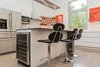 The extended countertop on the island provides a casual dining option and lets guests watch the cook at work. A wine cooler is tucked into one end of the island. Photo 20 of The Serdar Net Zero-Net Positive Micropolis® House modern home