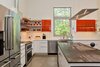 Modern home with Recessed Lighting, Concrete Floor, and Pendant Lighting. The white subway-tiled backsplash and open shelving make the kitchen look brighter and more spacious. The wrap-over counter top on the island looks like weathered steel but it's actually Dekton®, a composite material. Photo 19 of The Serdar Net Zero-Net Positive Micropolis® House