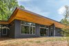 Modern home with Exterior, House Building Type, Metal Roof Material, Concrete Siding Material, and Shed RoofLine. The deep, angled, wood-clad soffit is an intriguing visual and textural contrast to the dark gray cement board exterior walls. Photo 2 of The Serdar Net Zero-Net Positive Micropolis® House