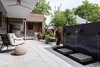 Modern home with Exterior, Metal Roof Material, Flat RoofLine, Metal Siding Material, House Building Type, and Wood Siding Material. The patio includes an outdoor kitchen (background) and a custom-fabricated steel water fountain. Photo 5 of The Thomas Residence